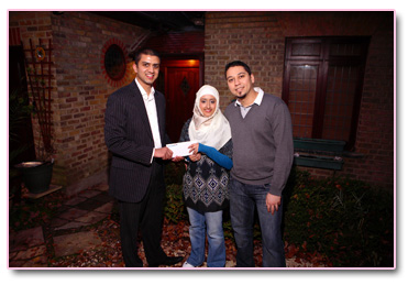 Adeem Younis presents Adam and  Safiyya with their Umrah tickets.